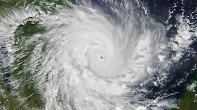 Cyclone clouds rotating over ocean and coastline, aerial satellite view. Contains public domain image by Nasa