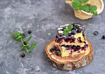 Sweet sliced cake with cornmeal and black currant. Decorated with fresh mint, powdered sugar and berries of frozen black currant.