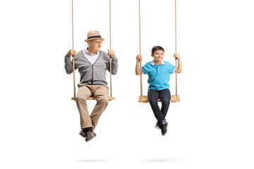 Grandfather looking at his grandson and sitting on wooden swings
