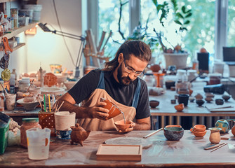 Diligent man is putting colourful clay to his new handmade pot. - obrazy, fototapety, plakaty