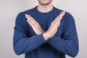 Close-up cropped photo portrait of confident handsome guy making demonstrating two crossed hands isolated grey background