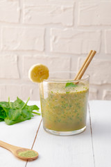 Detox recipe of spinach, banana, matcha smoothie on white wooden background. Image with copy space.