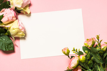 Empty paper sheet and flowers on pink background.