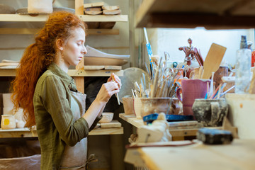 Focused long-haired ginger girl checking state of her tools
