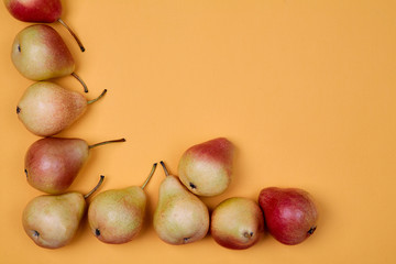 Ripe juicy pears placed on orange background. Colorful fruit pattern or background.