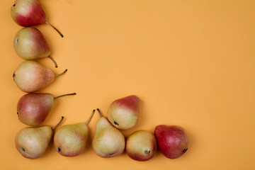 Ripe juicy pears placed on orange background. Colorful fruit pattern or background.