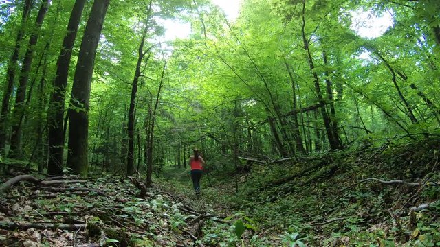 Beautiful overweight woman running down a path through forest