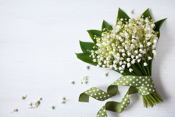 Bouquet flowers of lily of the valley on a white wooden background