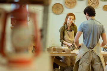 Curious ginger curly girl listening to her master while staying in decorated workshop