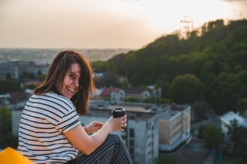 Fototapeta na wymiar woman drinking coffee with beautiful view of sunset over lviv city in ukraine