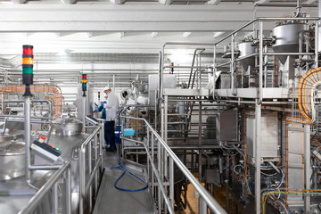 worker in a blue robe and a cap inspect the production department of dairy factory