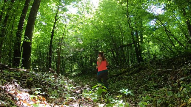 Overweight woman running down a forest path on a sunny day