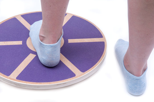 Woman's foot on Wooden Wobble Balance Board Exercise Core Fitness Trainer for Workout, Fitness, Balance Exercise & Rehabilitation.