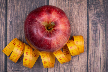 Red Apple and Soft Vinyl Measuring Tape on wooden background.