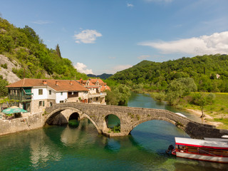 Fototapeta na wymiar Aeral view to old bridge in the village Rijeka Crnojevica reflecting in the water in Montenegro. Stari most.