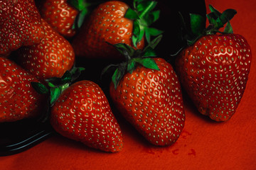 Fresh juicy strawberries with leaves. Strawberry on a red background