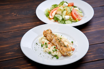 chicken kebab with rice and vegetables on the wooden background