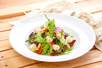 vegetarian salad with dried tomatoes and croutons on the wooden background