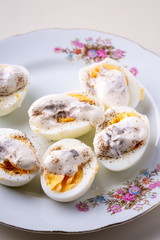 Sliced boiled eggs with mayonnaise and pepper in white plate isolated angle view