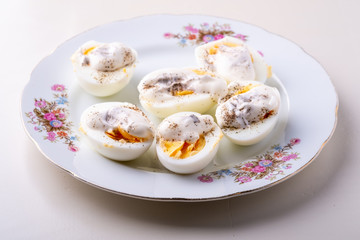 Sliced boiled eggs with mayonnaise and pepper in white plate isolated angle view