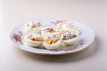 Sliced boiled eggs with mayonnaise and pepper in white plate isolated angle view