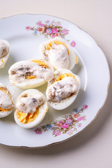 Sliced boiled eggs with mayonnaise and pepper in white plate isolated angle view