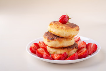 Obraz na płótnie Canvas Cottage cheese pancakes with sliced strawberries on white plate isolated