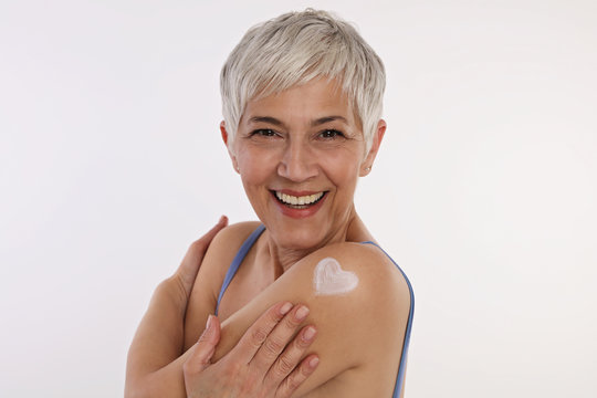 Sun Protection, Mature Skin Care . Woman Applying Moisturizing Cream, Hugging Herself .