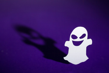 Halloween background concept. Funny ghost and graphic shade, hard light on purple table.