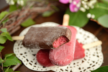 fruit ice cream on a stick, on a background of green leaves