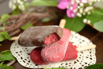 fruit ice cream on a stick, on a background of green leaves