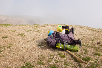 Backpack on a brink rock. Mountain in the mist.