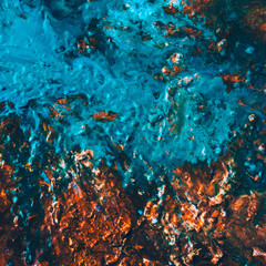 Fototapeta na wymiar Abstract art texture background. Closeup of hazelnut brittle with colorful glaze. Glossy blue and brown paint with flowing effect.