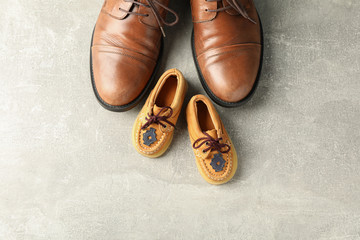 Brown leather shoes and children's shoes on grey background, space for text and top view