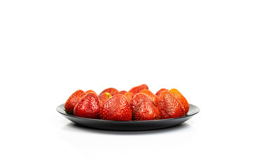 Fresh strawberry fruit in black plate isolated on white background.