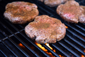 Grilling seasoned burgers on a barbecue