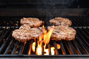 Grilling burgers on a barbecue with flames