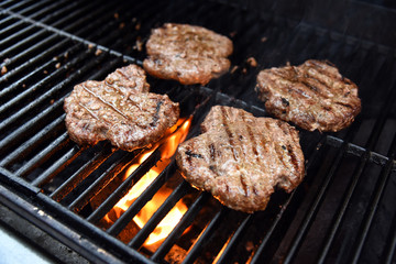 Grilling burgers on a barbecue with flames