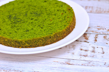 green round spinach mint cake on a white plate on the table with shabby boards