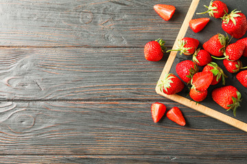 Fototapeta na wymiar Cutting board and fresh strawberries on wooden table, top view and space for text. Summer sweet fruits and berries