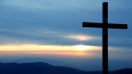 wooden cross on a background of sunrise in the mountains.
