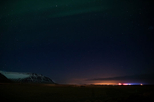 Aurora Borealis with a snowy mountain and city lights