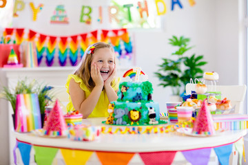 Obraz premium Child birthday party. Kids blow candle on cake.