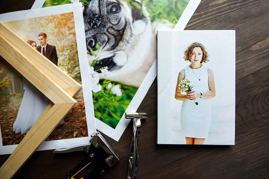 Photo canvas prints. Tools for wrapping.  Photographs, stretcher bars, staple gun and canvas pliers.  Printed photos of a dog and a wedding couple lying on a wooden table. Top view