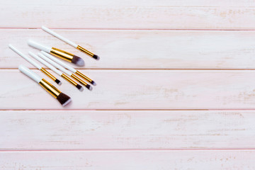 Set of makeup brushes on pink wooden background