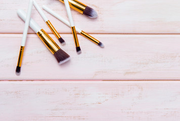 Set of makeup brushes on pink wooden background