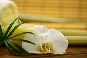 Spa towels, candle and orchid on bamboo blurred background.