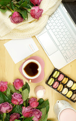 Feminine desk or workspace coffee break time overhead flatlay with modern hi tech laptop and scattered roses.
