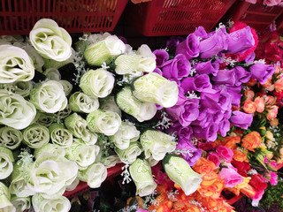  Colorful artificial flowers made of plastic display vertically in in shops for sale. 