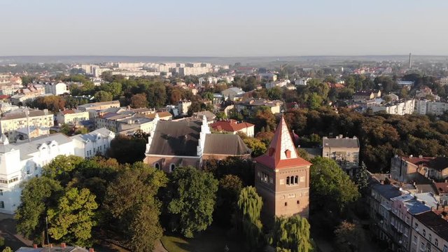 Aerial view of Drohobych city, Ukraine. Bell tower and ancient church St. Bartholomew, downtown. Established shot, pull forward, 4K